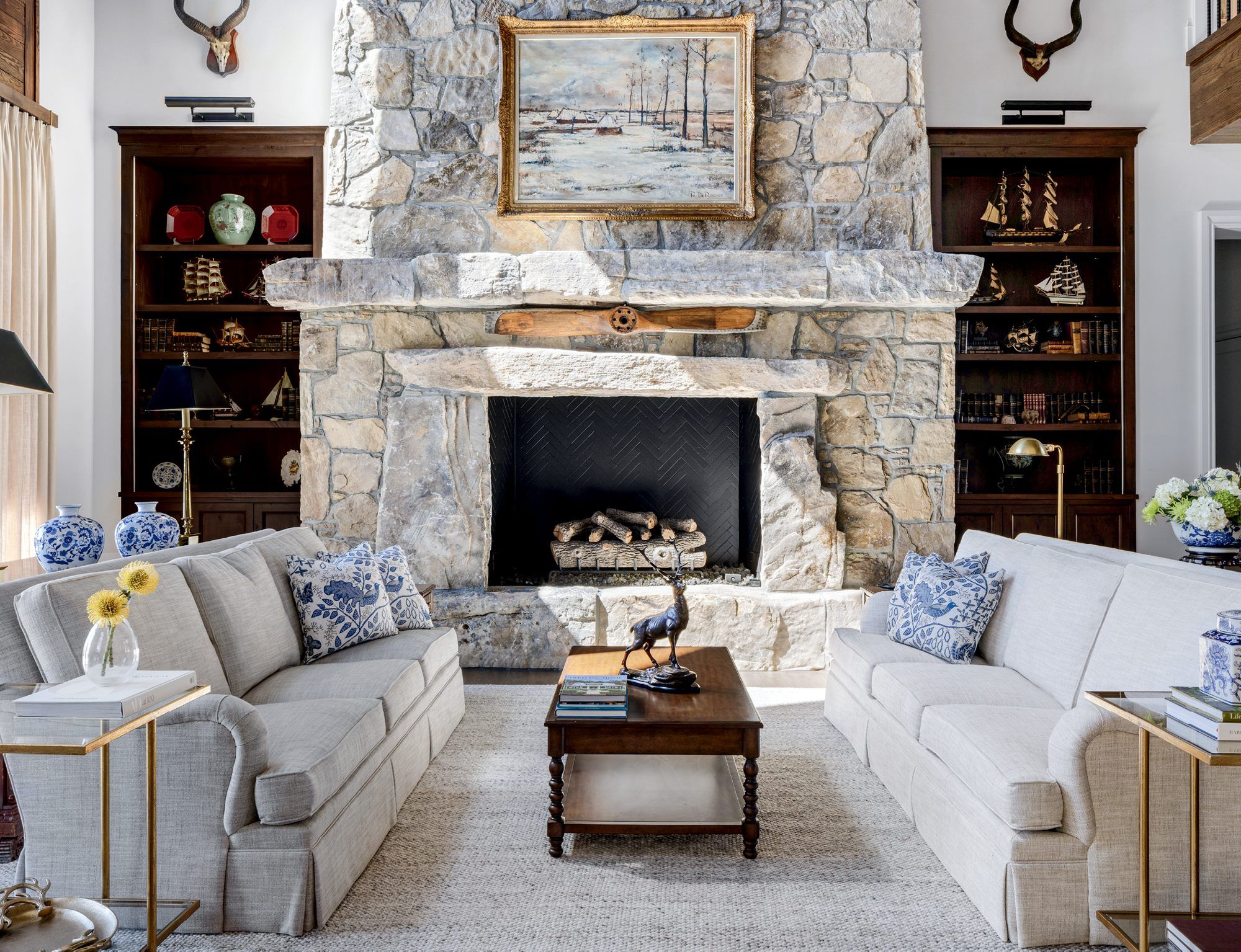 A great room built around a full-height stone fireplace with a rough-hewn stone mantel