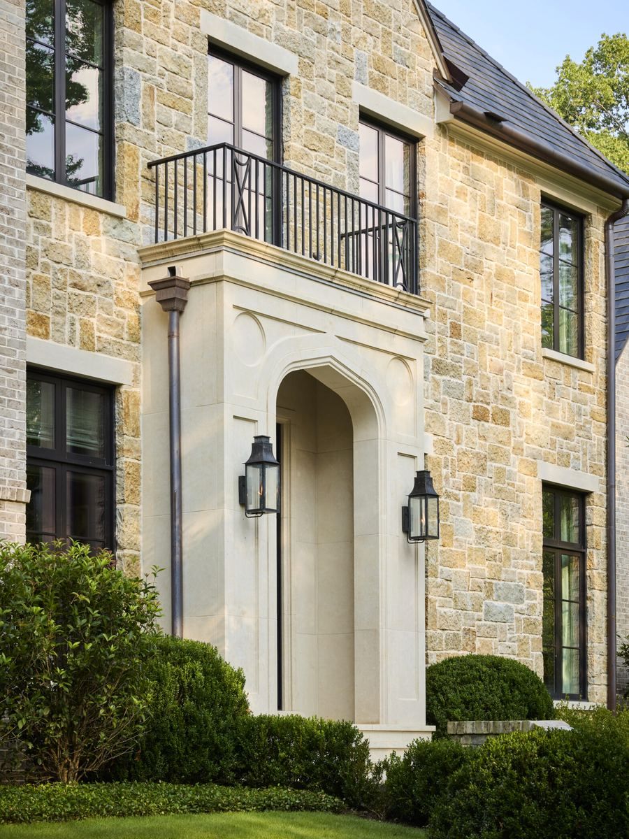 A carved limestone entry surround with iron lanterns